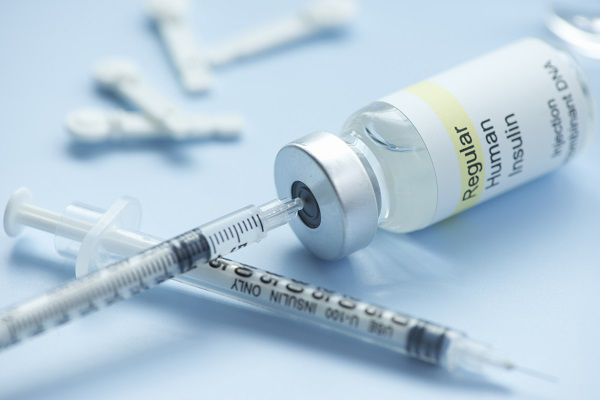 Photo of a needle with a bottle of insulin